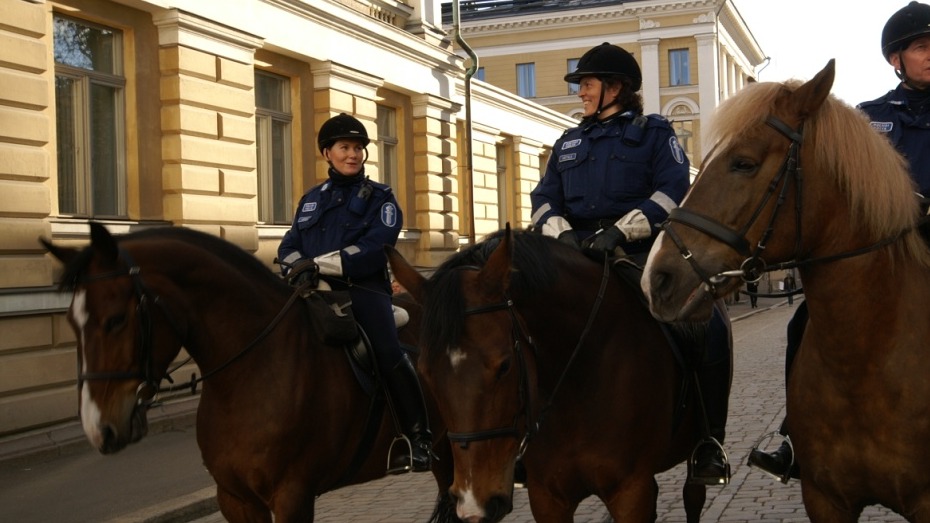 Three Finnish Police mounted officers on horseback on a cobbled street in central Helsinki
